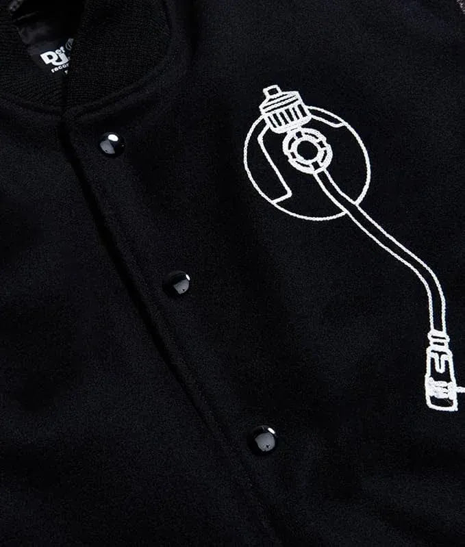 Zoom  catalog layout of the Leveljacket Def Jam Recordings black varsity jacket, displaying a premium black wool body with black leather sleeves, custom white embroidered turntable needle art on the front chest, and a bold white Def Jam Recordings typography patch layout across the back.