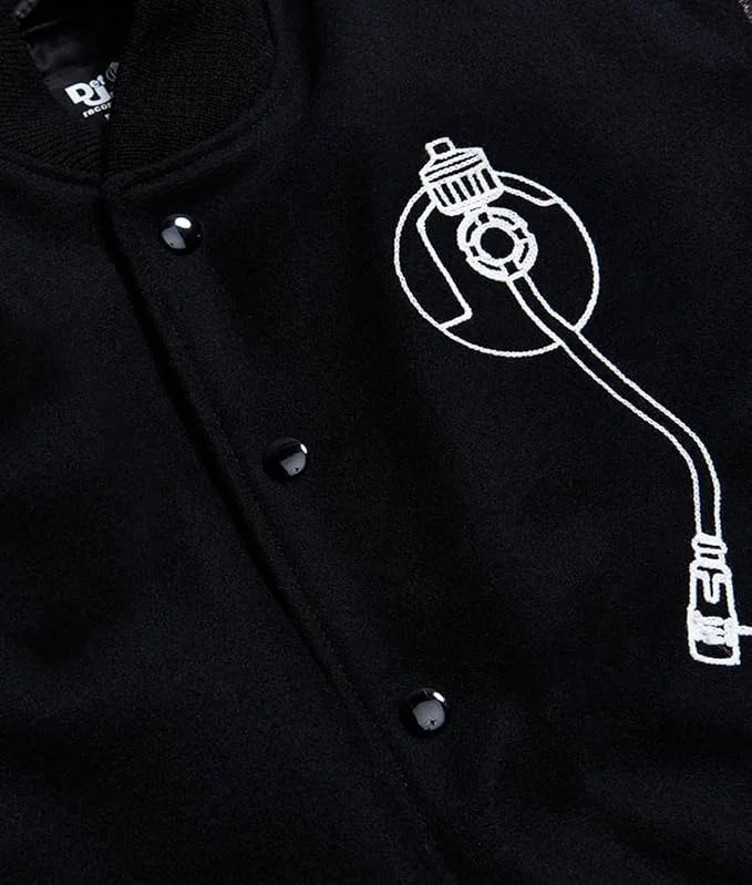 Zoom  catalog layout of the Leveljacket Def Jam Recordings black varsity jacket, displaying a premium black wool body with black leather sleeves, custom white embroidered turntable needle art on the front chest, and a bold white Def Jam Recordings typography patch layout across the back.