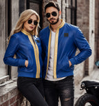 Two people wearing matching blue leather jackets standing in an urban setting.